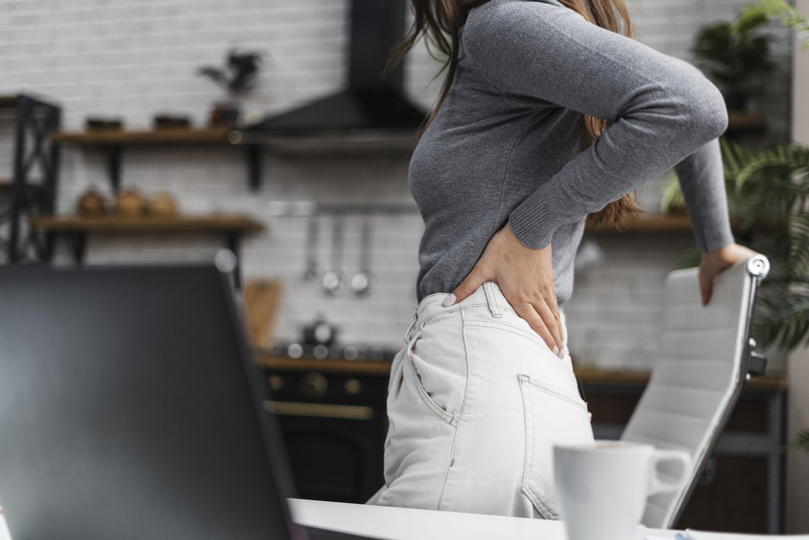 side view woman having backache while working from home scaled